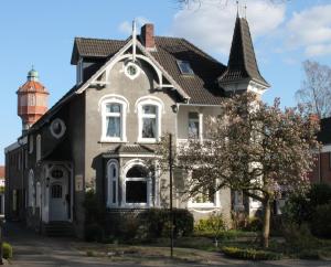 an old house with a lighthouse in the background at Alleehotel-Eschen in Aurich