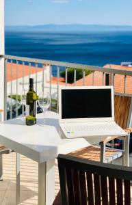 einen weißen Tisch mit einer Flasche Wein und einem Laptop in der Unterkunft Guest House Stipe in Brela
