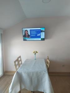 a table with a vase on it with a tv on the wall at Nores Buenavista 2 in Vilaboa