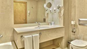 
a bathroom with a toilet, sink and mirror at Hotel Cinquentenario & Conference Center in Fátima
