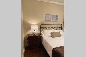 Un dormitorio con una cama y una lámpara en un tocador en Mill Cottage, en Tupelo