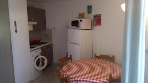 una pequeña cocina con mesa y nevera blanca en Studio de 27 m² + 70 m² de jardin à 100 m des plages, en Cavalaire-sur-Mer