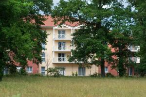 un grand bâtiment rose avec des arbres devant lui dans l'établissement Domitys Le Parc Saint Germain, à Montrond-les-Bains