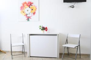 due sedie e un tavolo con un dipinto di fiori sul muro di Ai due leoni a Capri Altre 4 foto