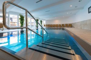 a swimming pool with stairs in a building at Appartementhotel Sonnenhof in Kössen