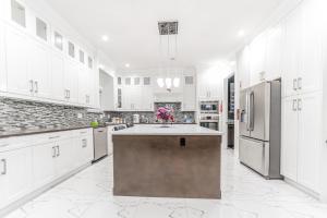 a large kitchen with white cabinets and a large island at Kim's Place in Surrey
