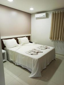 ein Schlafzimmer mit einem weißen Bett und Handtüchern darauf in der Unterkunft Hotel Roni in Itabuna