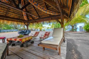 una terraza de madera con sillas, una mesa y un banco en TAHITI - Taharuu Houses Surf & Beach, en Papara