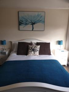 a bedroom with a large bed with a blue blanket at Highfield Guest House in Sheringham