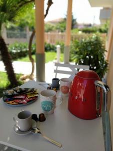 una mesa con una tetera roja y tazas. en Villa Joy - Iconic Heritage Rooms, en Montesilvano