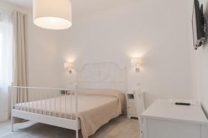a small white bedroom with a bed and a desk at Amare Sirolo in Sirolo