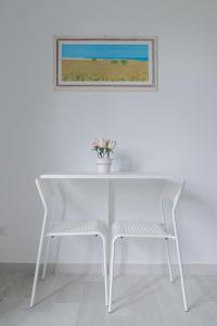 Amare Sirolo في سيرولو: طاولة بيضاء مع كرسي وصورة على الحائط