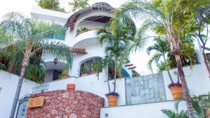 a white building with palm trees in front of it at Mi Otra Casa in Sayulita
