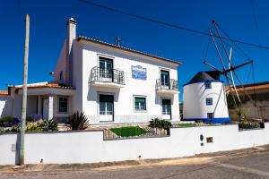 una casa blanca con un molino de viento delante de ella en Casa do moleiro en Encarnação