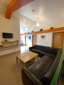 ein Wohnzimmer mit einem schwarzen Ledersofa und einem Tisch in der Unterkunft Hörgsland Guesthouse in Hörgsland