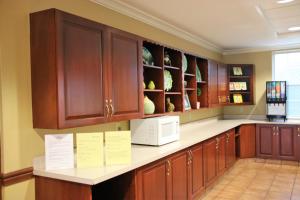 cocina con armarios de madera y microondas blanco en Hawthorn Suites by Wyndham Louisville East en Louisville