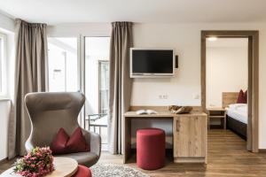 a living room with a room with a bed and a television at Hotel Zum Löwen - Al Leone in Meltina