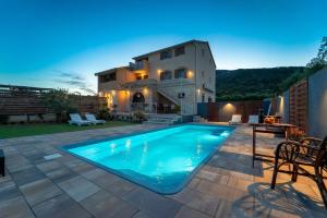 a swimming pool in front of a house at Apartments Mardešić in Komiža