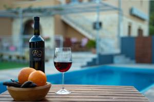 a bottle of wine and a bowl of oranges and a glass at Apartments Mardešić in Komiža