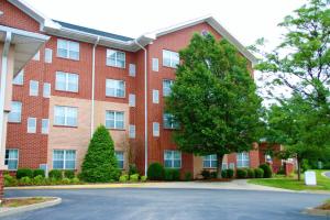 um edifício de tijolos vermelhos com uma árvore em frente em Hawthorn Suites by Wyndham Louisville East em Louisville