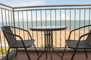 una mesa y sillas en un balcón con vistas a la playa en International Seaview Apartments, en Lignano Sabbiadoro