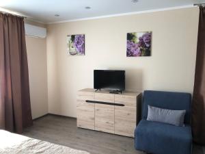 a living room with a tv and a blue chair at Apartments IRIS in Chornomorsk