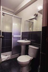 a bathroom with a toilet and a sink and a shower at Hotel Suite Plaza in Trujillo