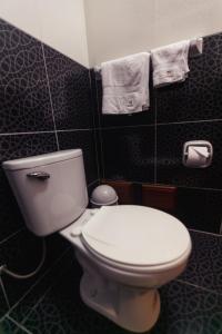 a bathroom with a toilet and towels on the wall at Hotel Suite Plaza in Trujillo