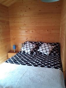 Cama en habitación con pared de madera en Domki Abiga, en Sianożęty