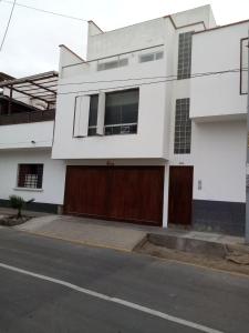 una casa blanca con puertas marrones en una calle en El Refugio, en Punta Hermosa