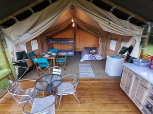 une tente avec une table et des chaises. dans l'établissement Safari at La Petite Lande, à Pierrefiche