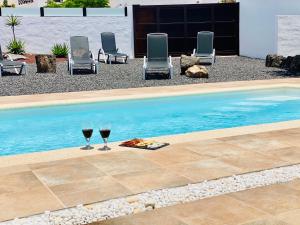 dos copas de vino sentadas junto a una piscina en Canaryislandshost l My Nest, en Nazaret