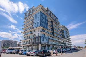 Un grand bâtiment avec des voitures garées dans un parking dans l'établissement Apartamente MRM Residence, à Mamaia Nord – Năvodari