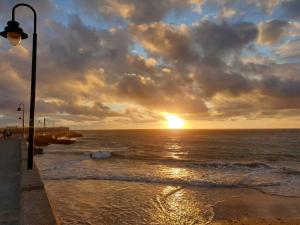 einen Sonnenuntergang über dem Meer mit Straßenbeleuchtung in der Unterkunft LUZ DEL FARO in Cádiz