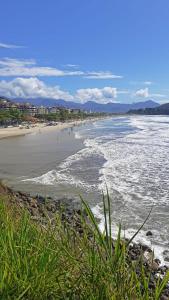 vistas a una playa con gente en el agua en Apartamento com ar condicionado à 100 metros da praia - Edifício Ibiza en Ubatuba