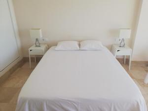 - un lit blanc dans une chambre avec deux tables dans l'établissement Castillo de Santa Clara 05, à Torremolinos