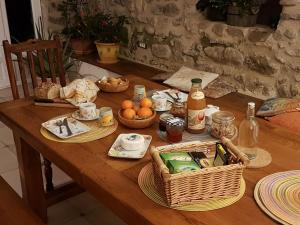 een houten tafel met eten, drinken en manden erop bij L'Attrape Rêve Insolite in Saint-Vincent-de-Barrès