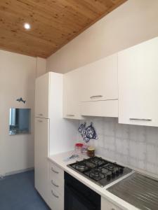 uma cozinha com armários brancos e um forno com placa de fogão em Appartamento Stella del mare em Trapani