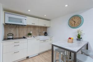 eine Küche mit weißen Schränken und einer Uhr an der Wand in der Unterkunft SoBe Lux Suites On Ocean in Miami Beach