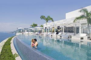 dos niños sentados en una piscina en un complejo en Hotel Mousai - Adults Only en Puerto Vallarta