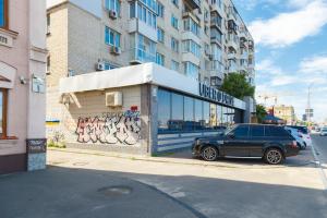 een auto geparkeerd voor een gebouw met graffiti bij Stylish apartment on Podol in Kiev