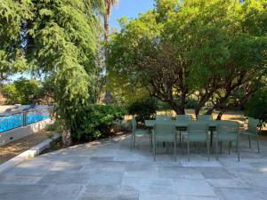 une table et des chaises sur un patio arboré dans l'établissement Grande propriété avec Piscine et Terrain de tennis privés, aux Lecques