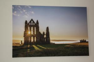 an old castle in a field with the sun setting behind it at No2 Abbey View Apartment in Whitby