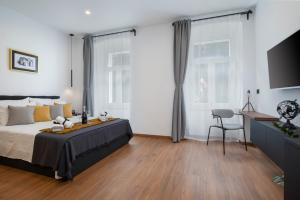 een slaapkamer met een bed, een bureau en 2 ramen bij Deluxe Rooms and Apartments Korzo in Pula