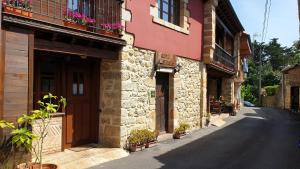 una calle en un edificio antiguo con flores en los balcones en Viviendas Rurales Costa de Bolao en Cóbreces