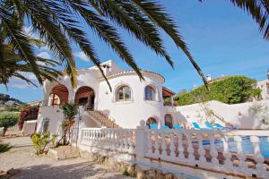 une maison blanche avec une clôture blanche et un palmier dans l'établissement San Jaime-19M - sea view villa with private pool in Moraira, à Pedramala