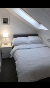 a bedroom with a large white bed with a skylight at Arran Ferry Apartment in Ardrossan