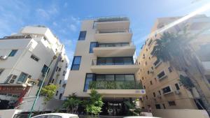 a tall white building with a palm tree in front of it at BnB Israel Apartments - Shalom Alehem Joie in Tel Aviv