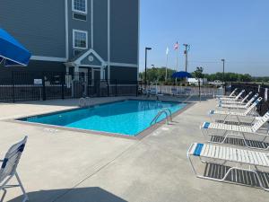 a swimming pool with lounge chairs next to a building at Microtel Inn & Suites by Wyndham Georgetown Delaware Beaches in Georgetown