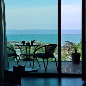 una mesa y sillas en un balcón con vistas al océano en Studio Tia, en Mamaia